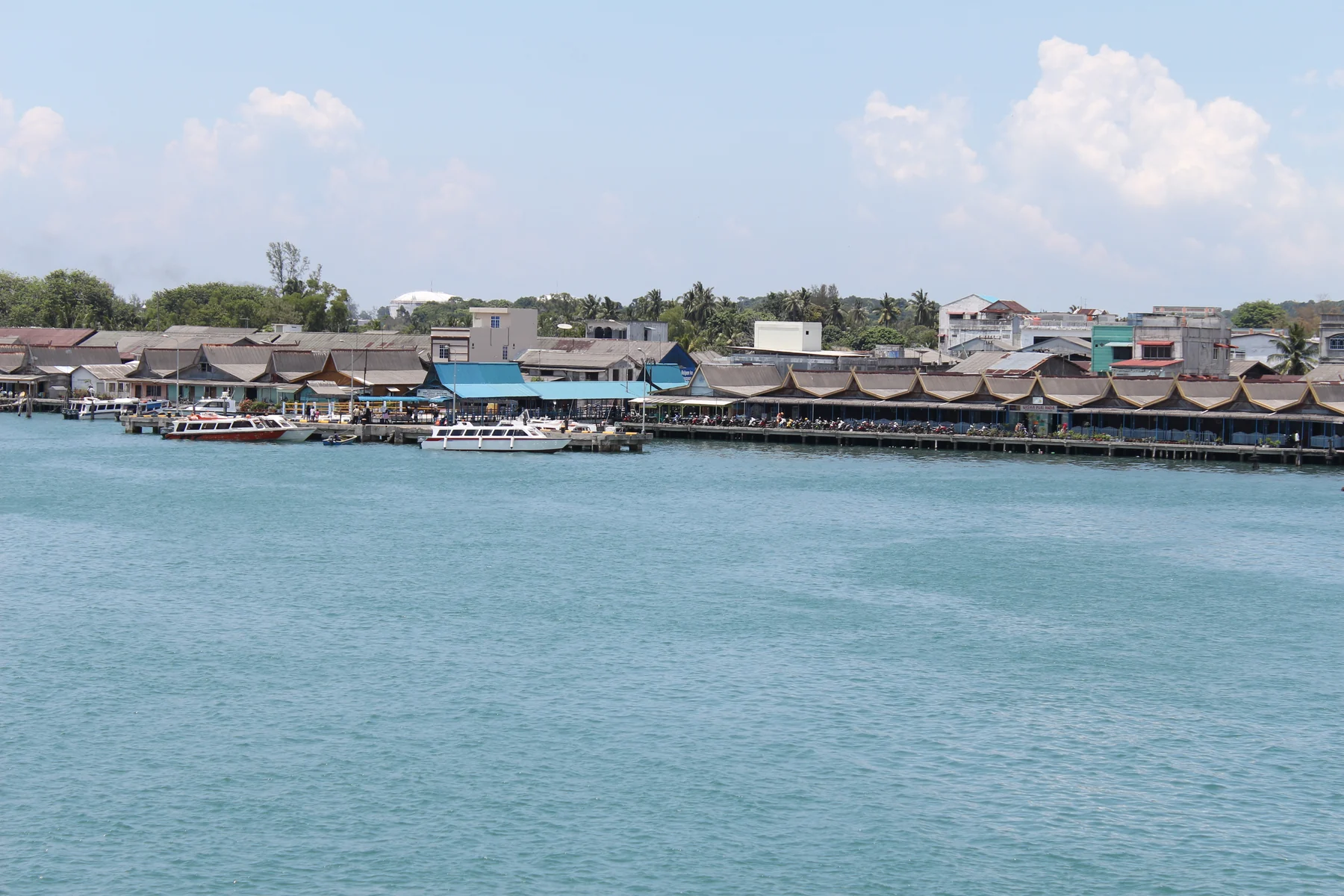 Dermaga, perahu, dan deretan bangunan di tepian Tanjung Uban dilihat dari perairan pada 2013